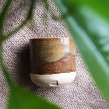 Small handmade, ceramic drinking vessel in brown.