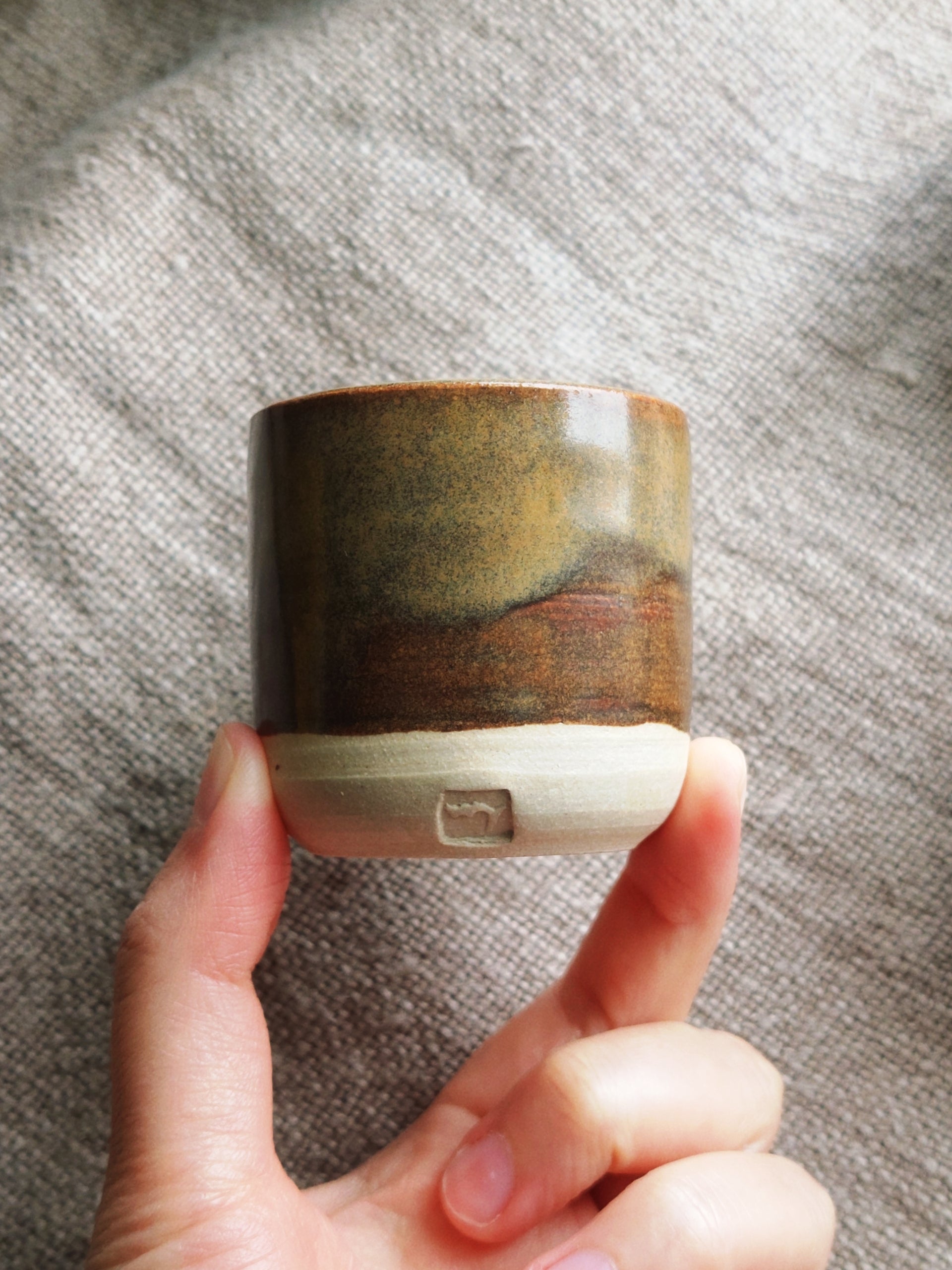 Hand holding small ceramic cup.