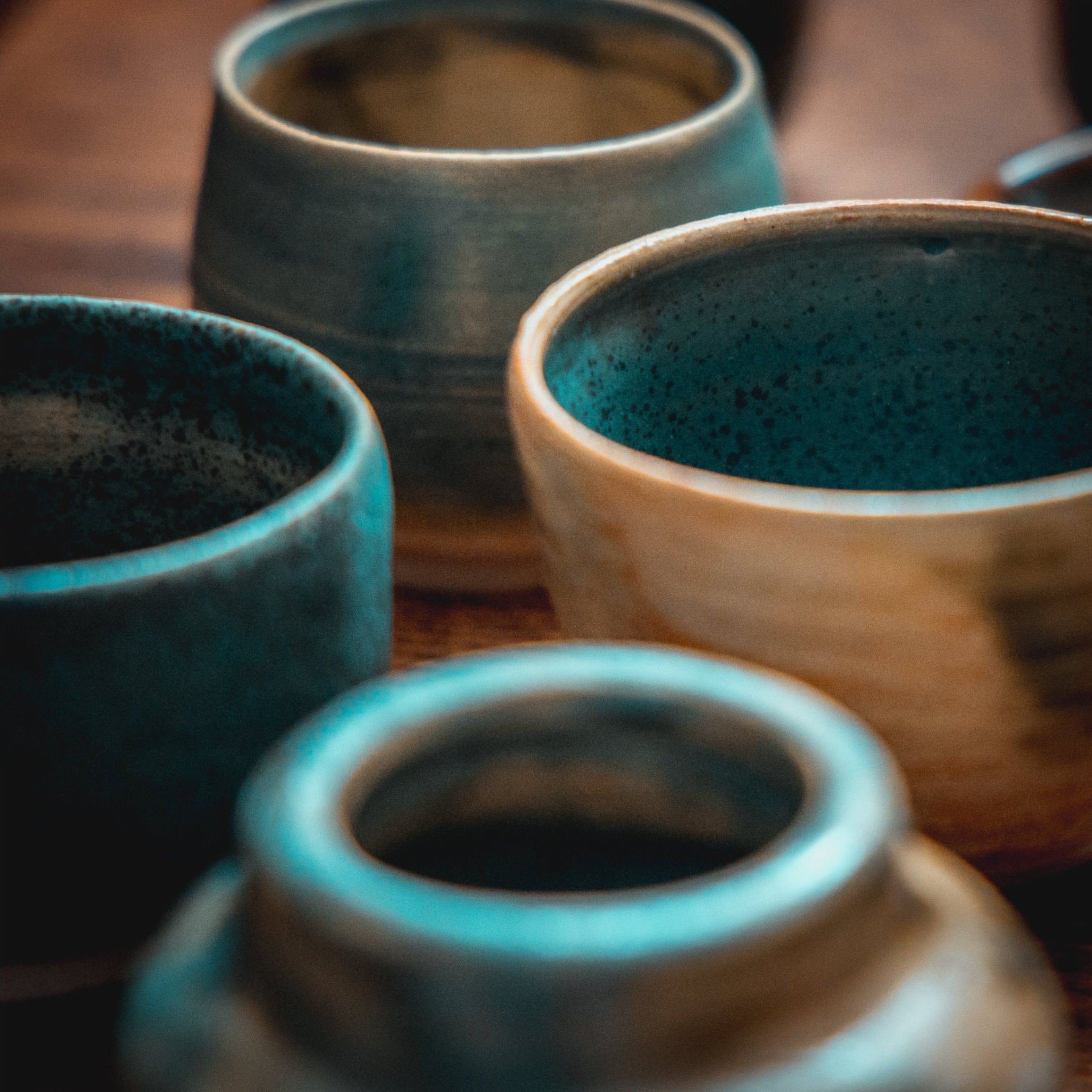 Four ceramic pots with a textured finish on a wooden surface