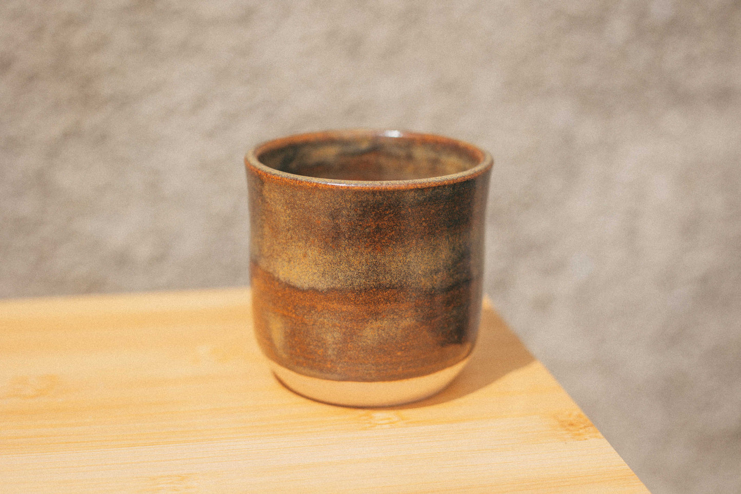 Ceramic cup with a brown glazed surface on a wooden surface